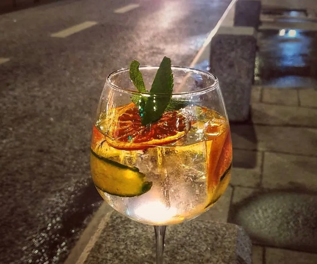 Gin tonic cu portocală deshidratată și mentă, seara, în centrul Bucureștiului